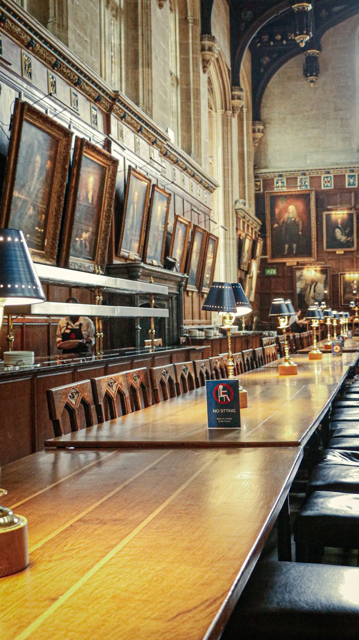 Services A grand historic dining hall adorned with classical paintings and elegant wooden furnishings.